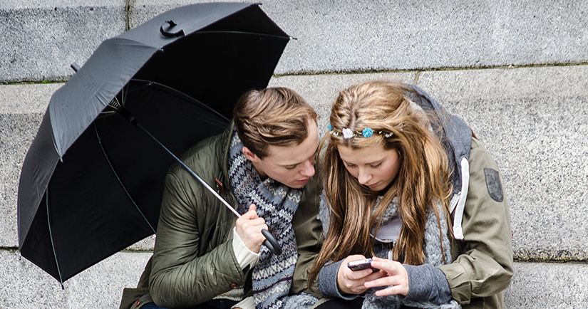 Photo of a teenage girl and guy looking at a cell phone