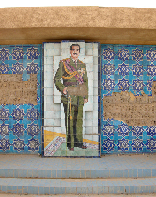 A mosaic of Saddam Hussein and other tile decorations are shown on a wall.