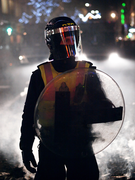 A masked officer with a shield is shown here.
