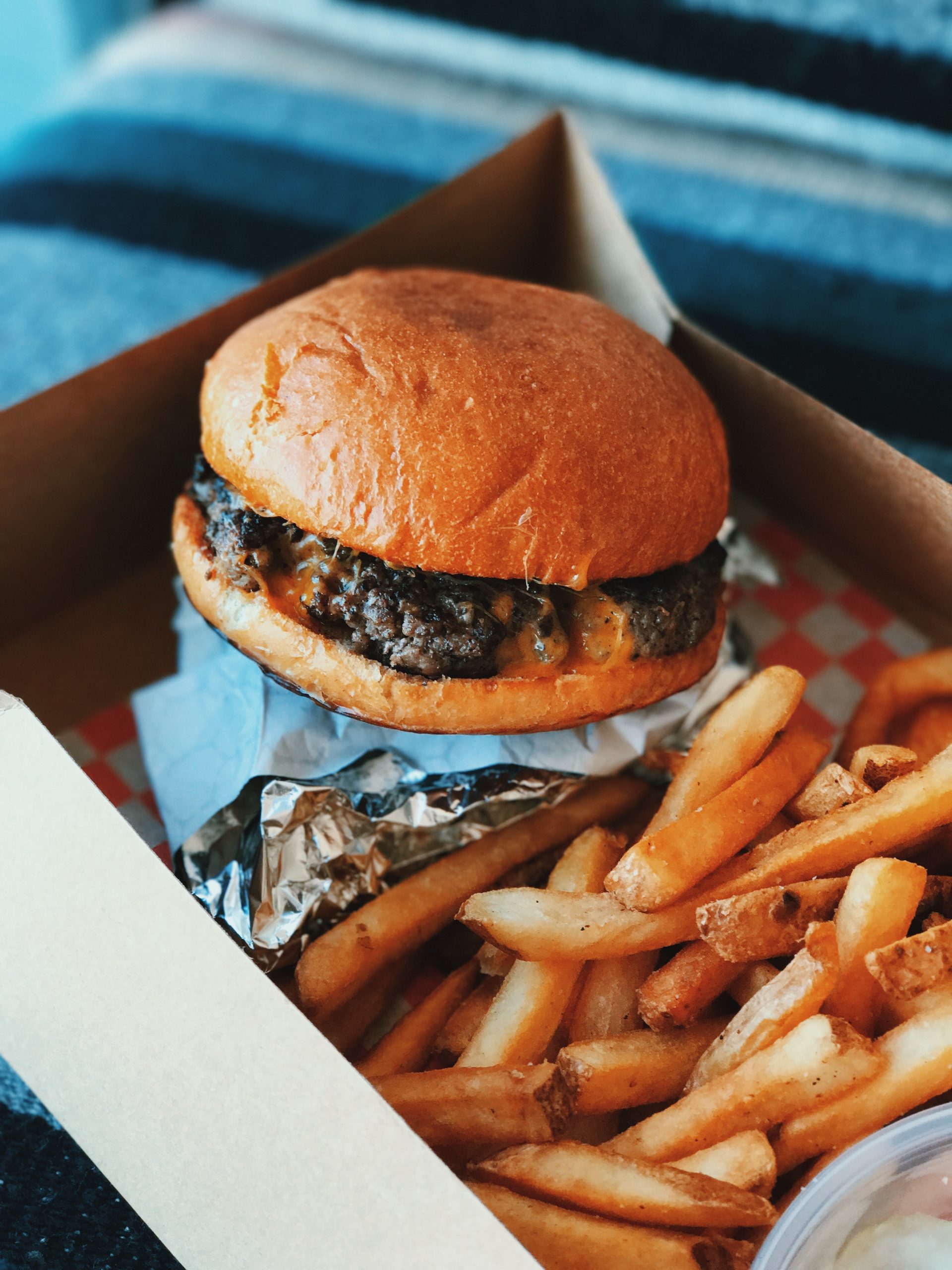 Image shows a cheeseburger and fries in a cardboard lunchbox.