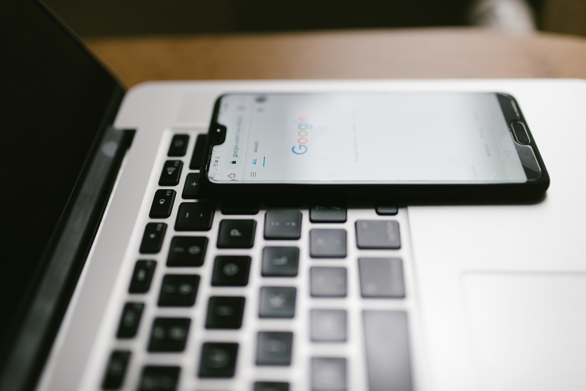 A smartphone lies face up on a laptop keyboard.