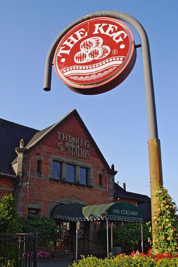 An old brick train station with a green entrance awning. A sign that says "The Keg" hangs on a pole.