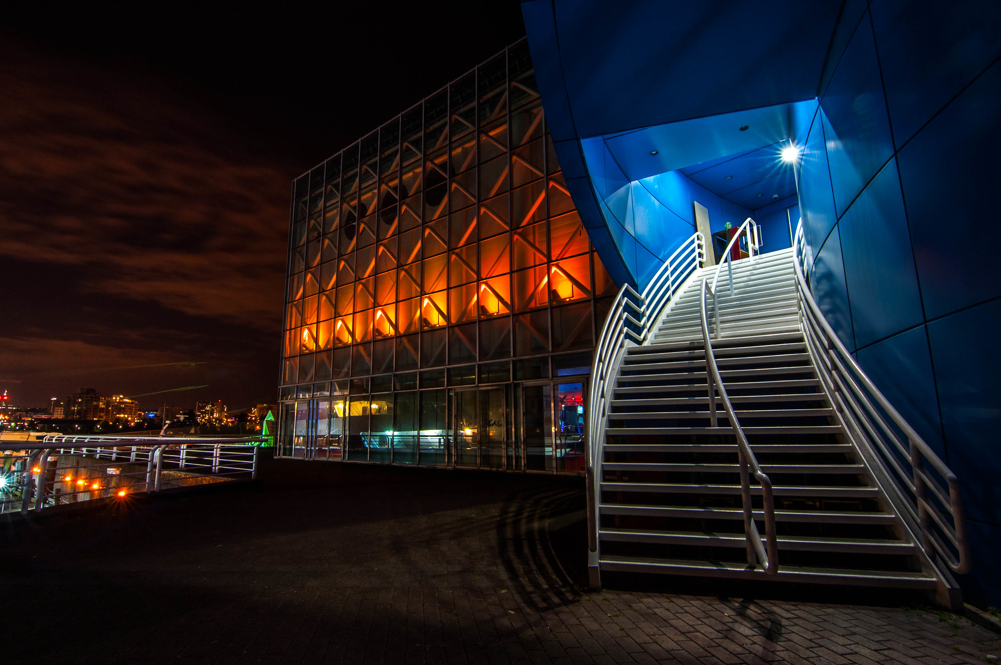 A curved staircase leading to an entrance of a building with floor-to-ceiling windows.