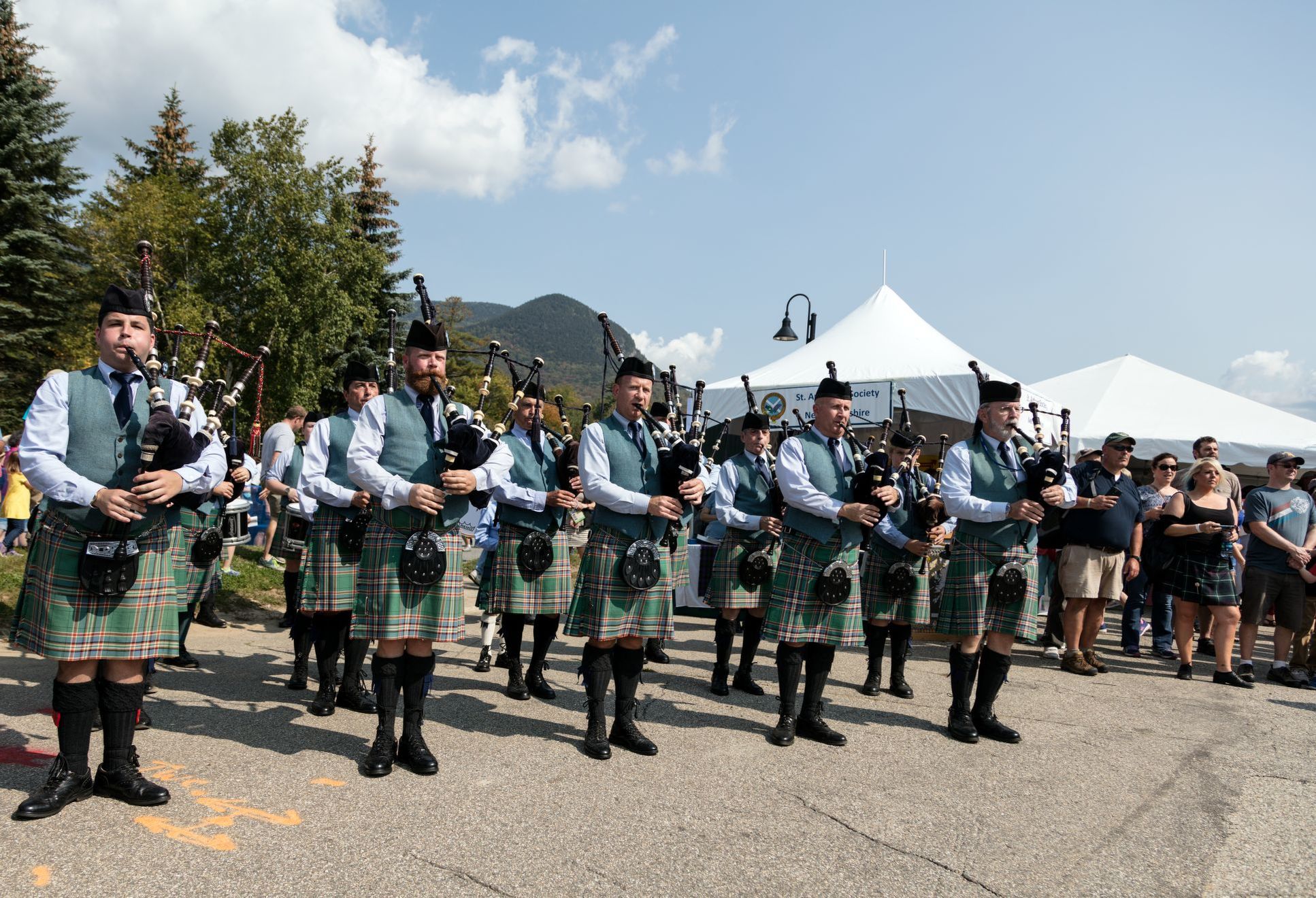 A group of Scottish men playing bagpipes and wearing kilts.