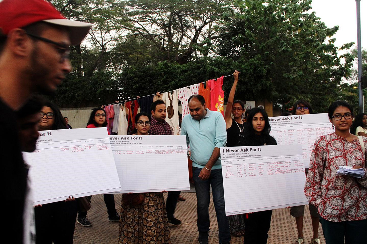 A group of people holding up signs that say "I Never Ask For It" with red handwriting beneath it.