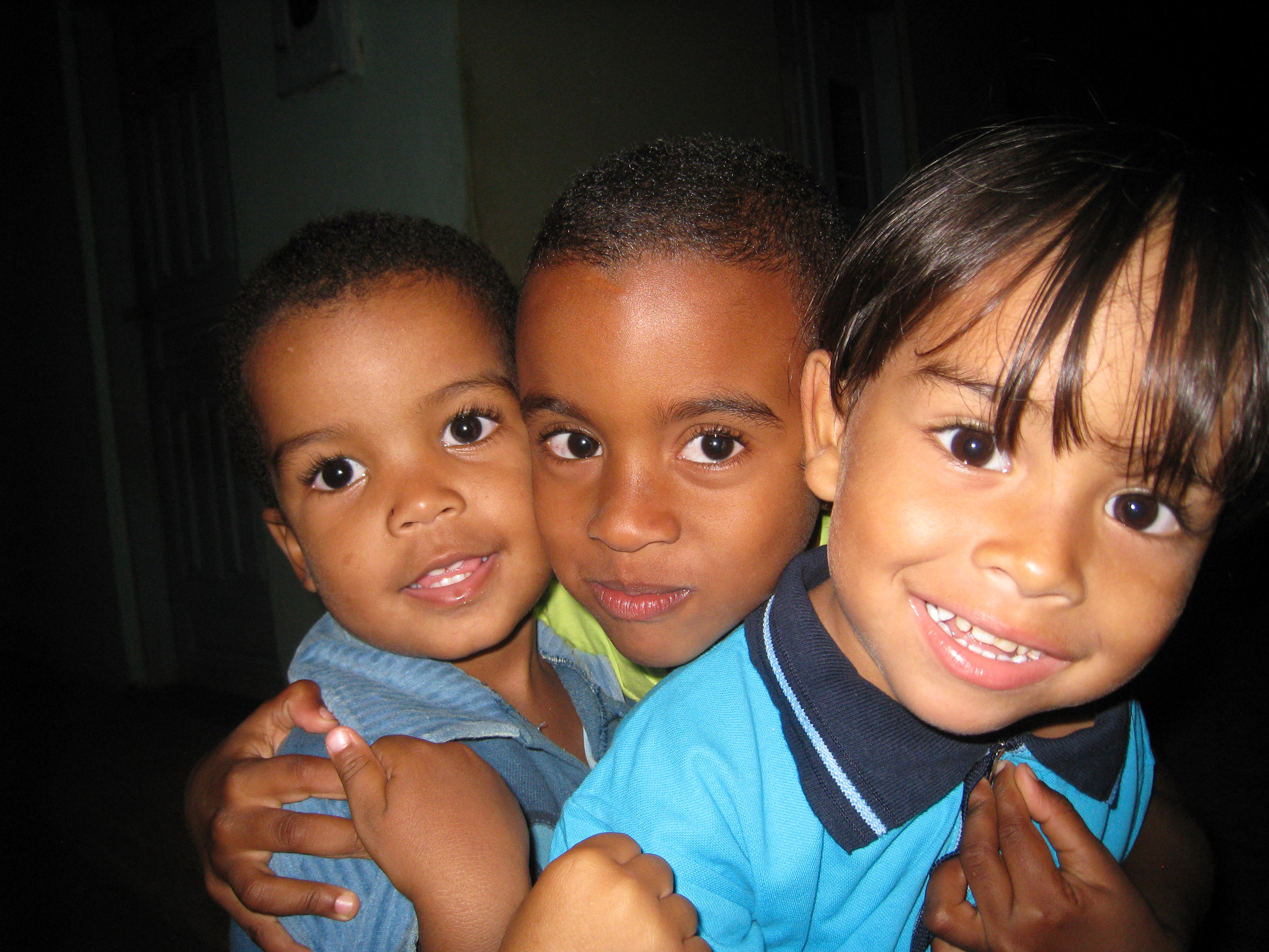 Three children hugging and smiling.