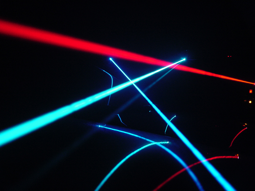 The image shows several red and blue colored laser beams rays that look similar to searchlights.
