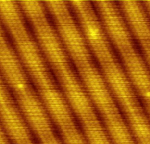 A pattern of diagonal lines in golden and brown color depicting gold atoms as observed with a scanning tunneling electron microscope.